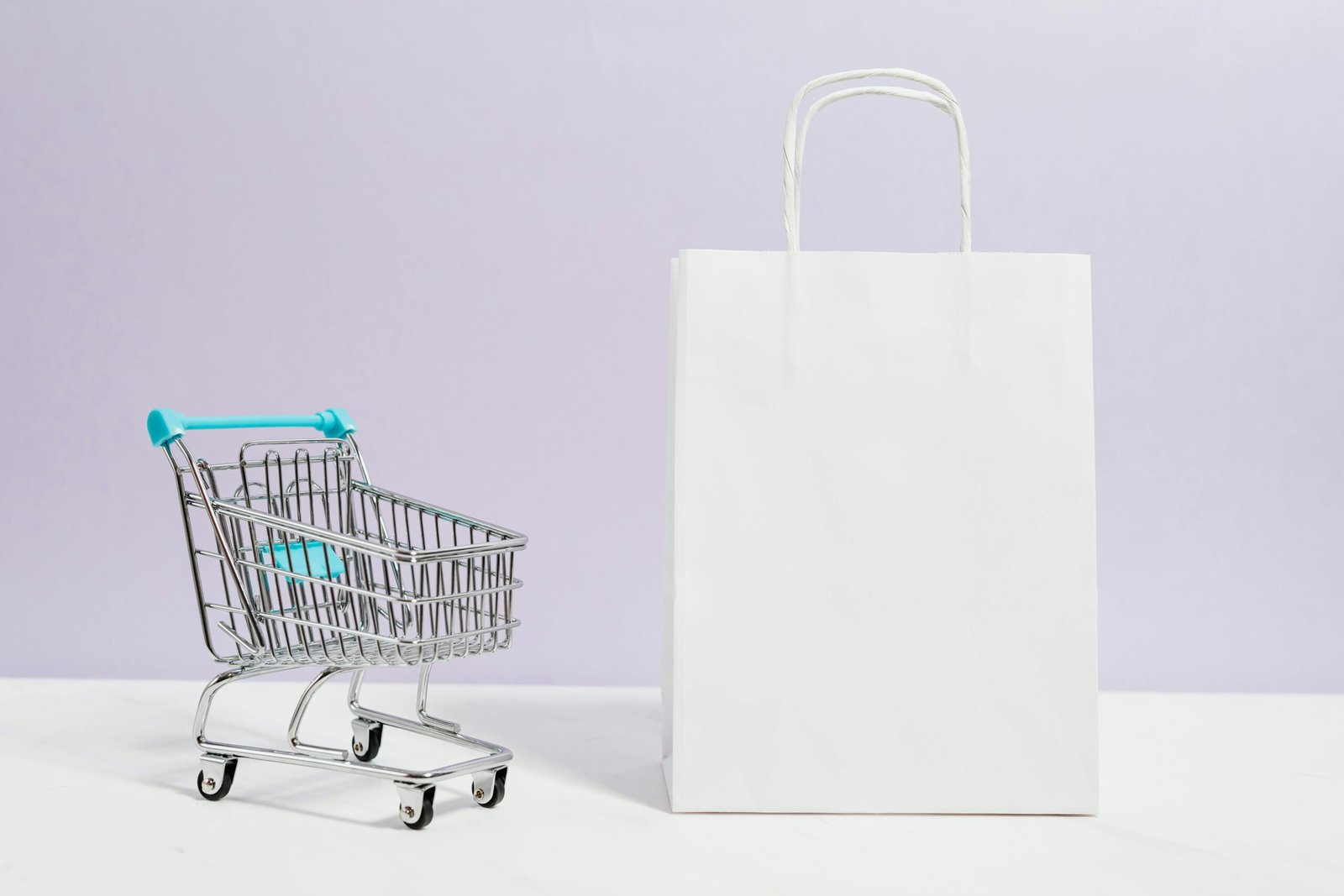 Saco de compras branco e pequeno carrinho sobre um fundo suave