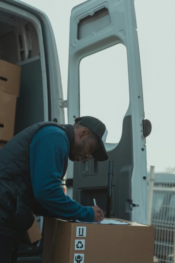 A delivery worker signs documents outside a parked van, managing logistics efficiently.